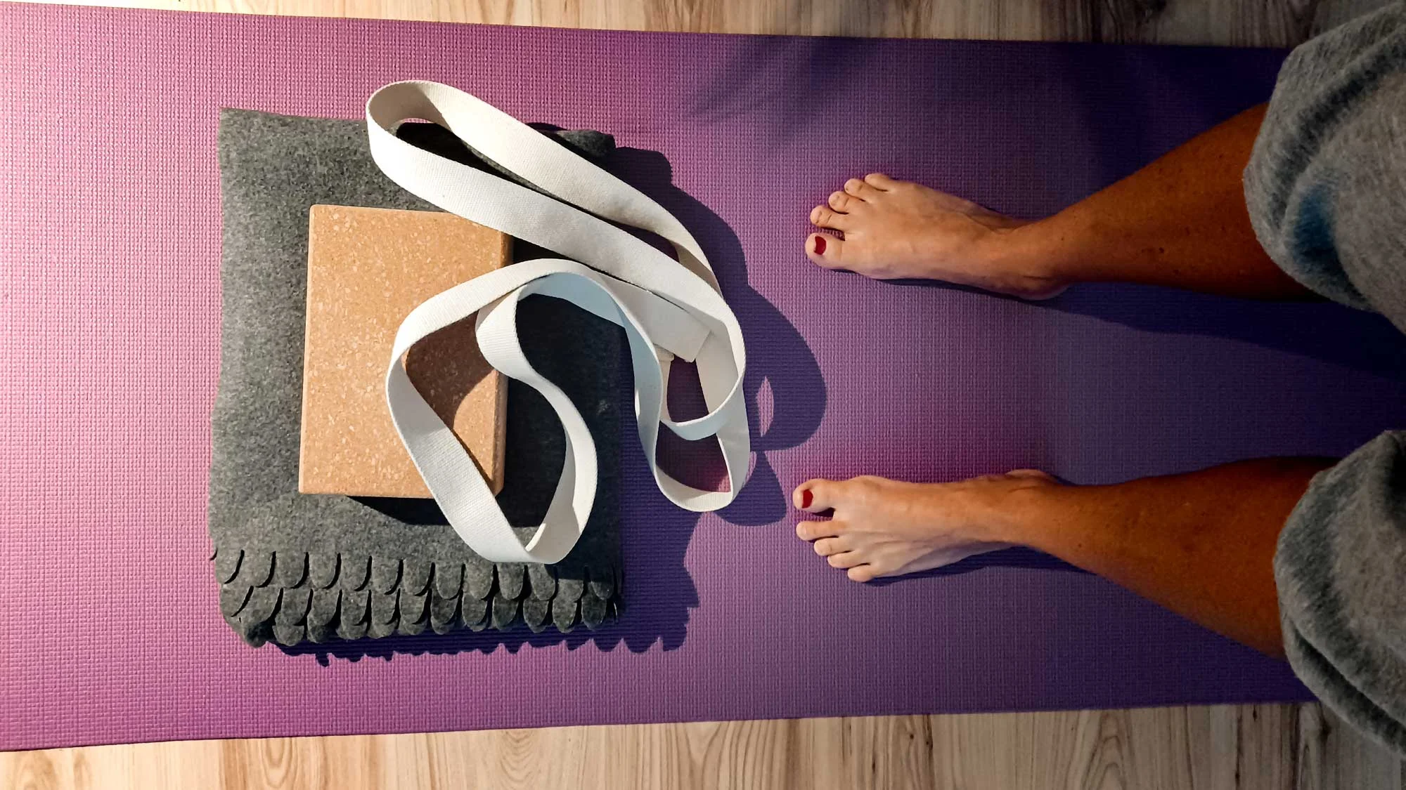 Nohy na jógové podložce s pomůckami na cvičení jógy